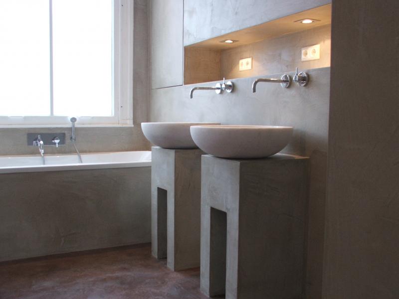Beton ciré op vloer en wand in een badkamer Badkamer met beton ciré op de vloer en de wanden, met twee opbouwkommen op een betonlook wasmeubel