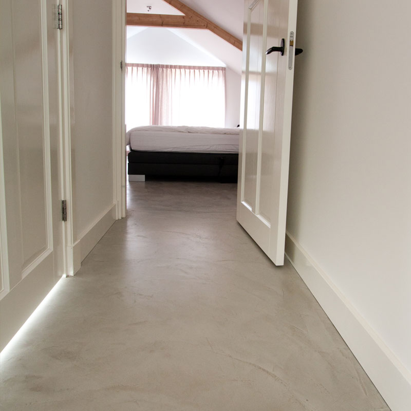 Beton ciré vloer op de overloop en in de slaapkamer Overloop met openslaande deuren naar een slaapkamer, op een naadloze beton ciré vloer in een zandtint