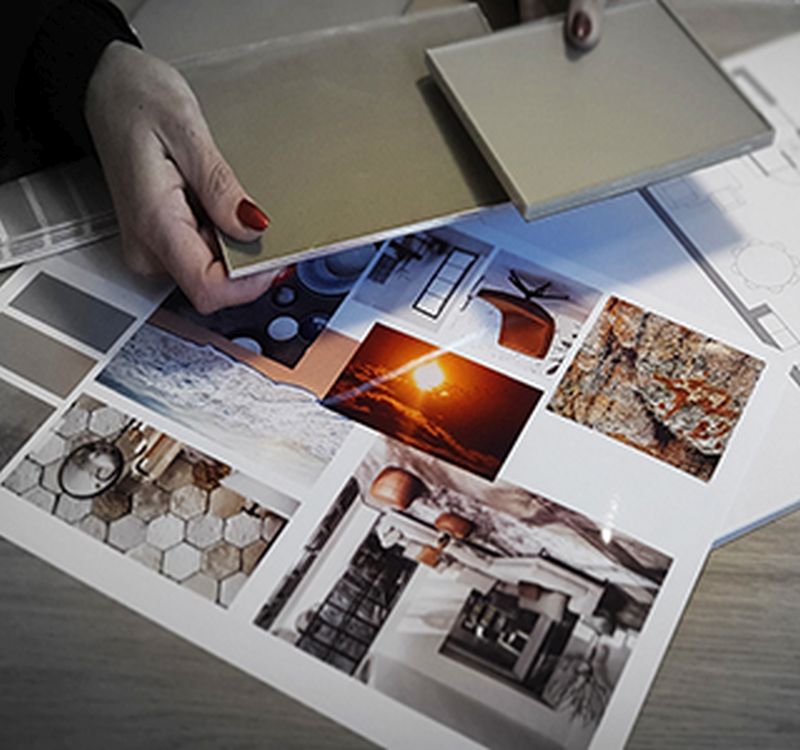 Materiaalstalen vergelijken in de showroom Hand houdt een kleurstaal boven een moodboard met interieurbeelden in de showroom in Son