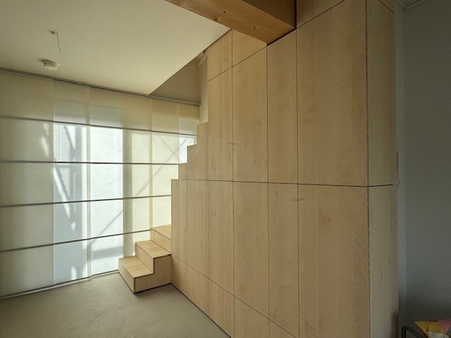 Keuken in japandistijl met een lichte woonbeton gietvloer en een houten kastenwand met trap naar boven