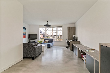 Doorkijk van woonkamer naar keuken over een naadloze microcement vloer in een lichtgrijze tint