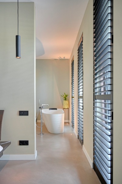 Badkamer met vrijstaand bad en houten lamellen, met een waterbestendige microcement vloer in een lichte tint