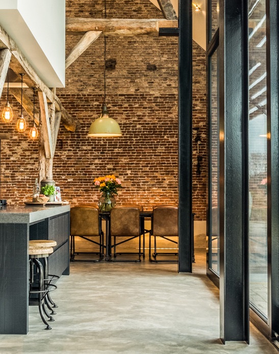 cementgebonden vloer in industrieel interieur met stalen accenten en baksteen muren.