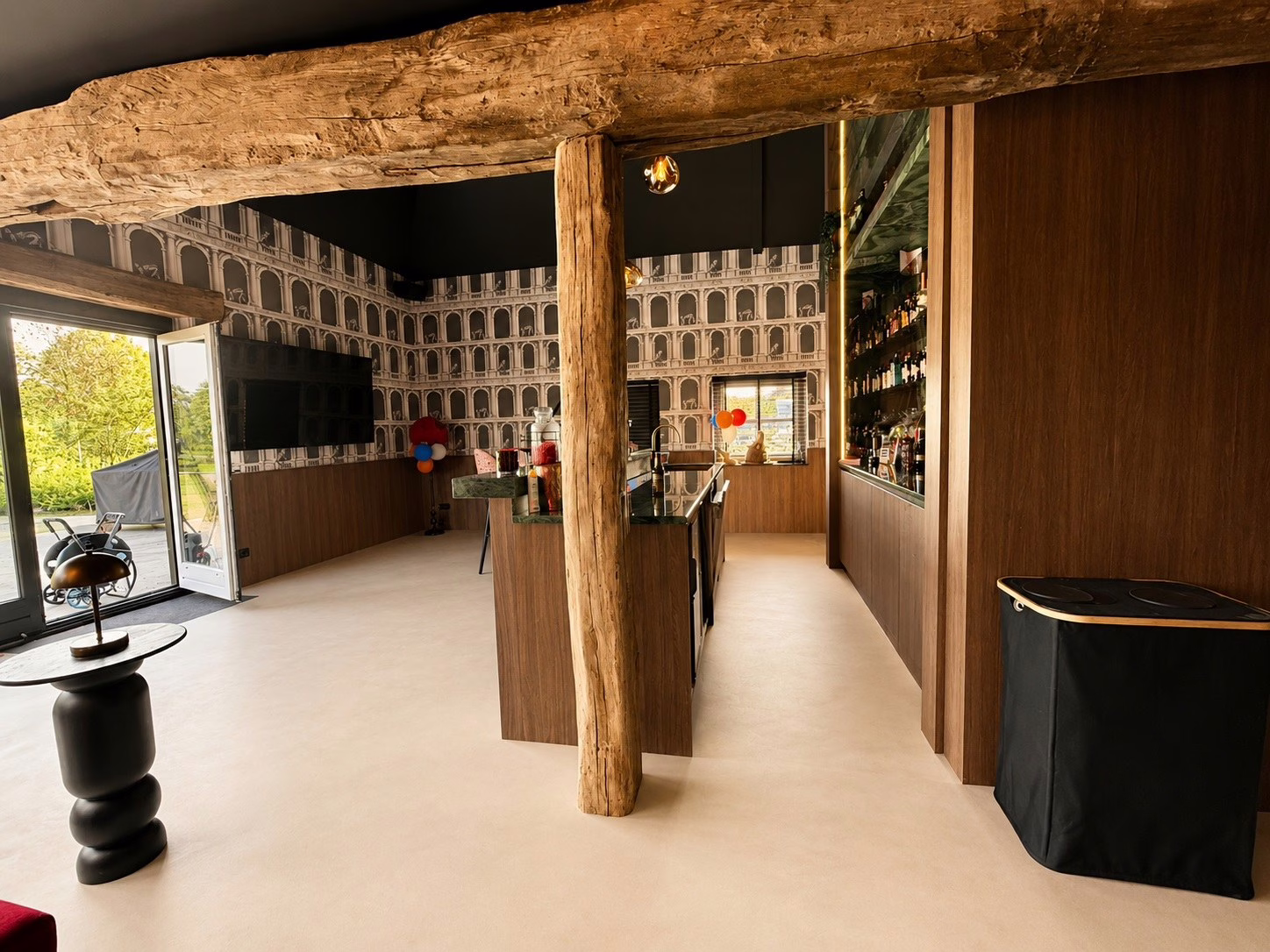 Minimal Sand gietvloer Best — rustieke moderne bar in een gemoderniseerde boerderij met oude houten balken.
