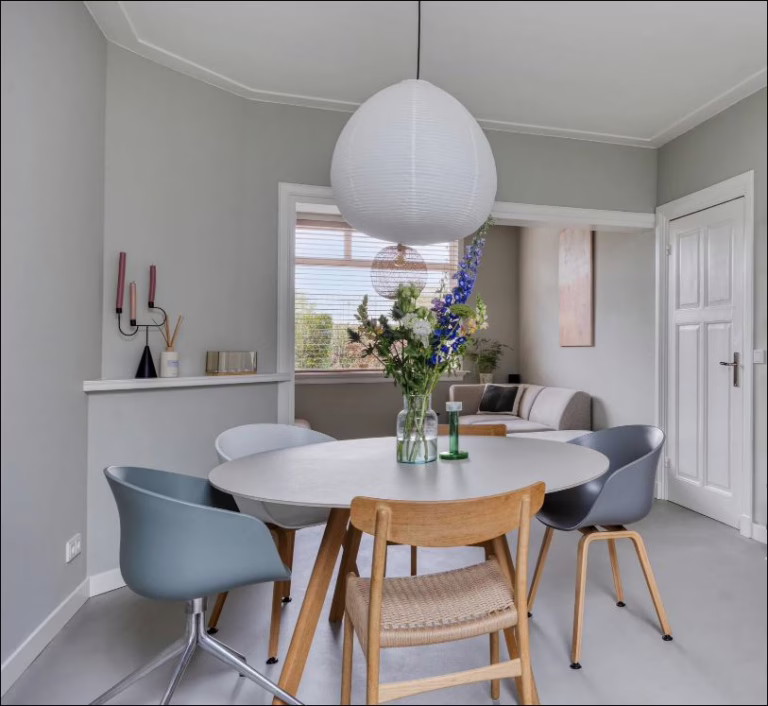 Detail eethoek met witte ronde tafel en Scandinavische stoelen op Lavasteen Premium gietvloer — Eindhoven
