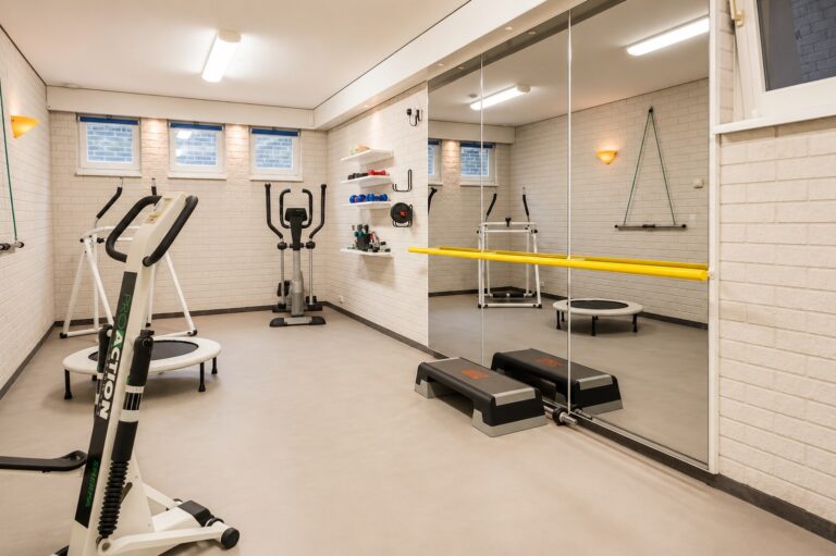 Overzicht van fitnessruimte met loopband en glazen pui op een lichtgrijze PU gietvloer NCS 2005-Y20, villa Schaijk