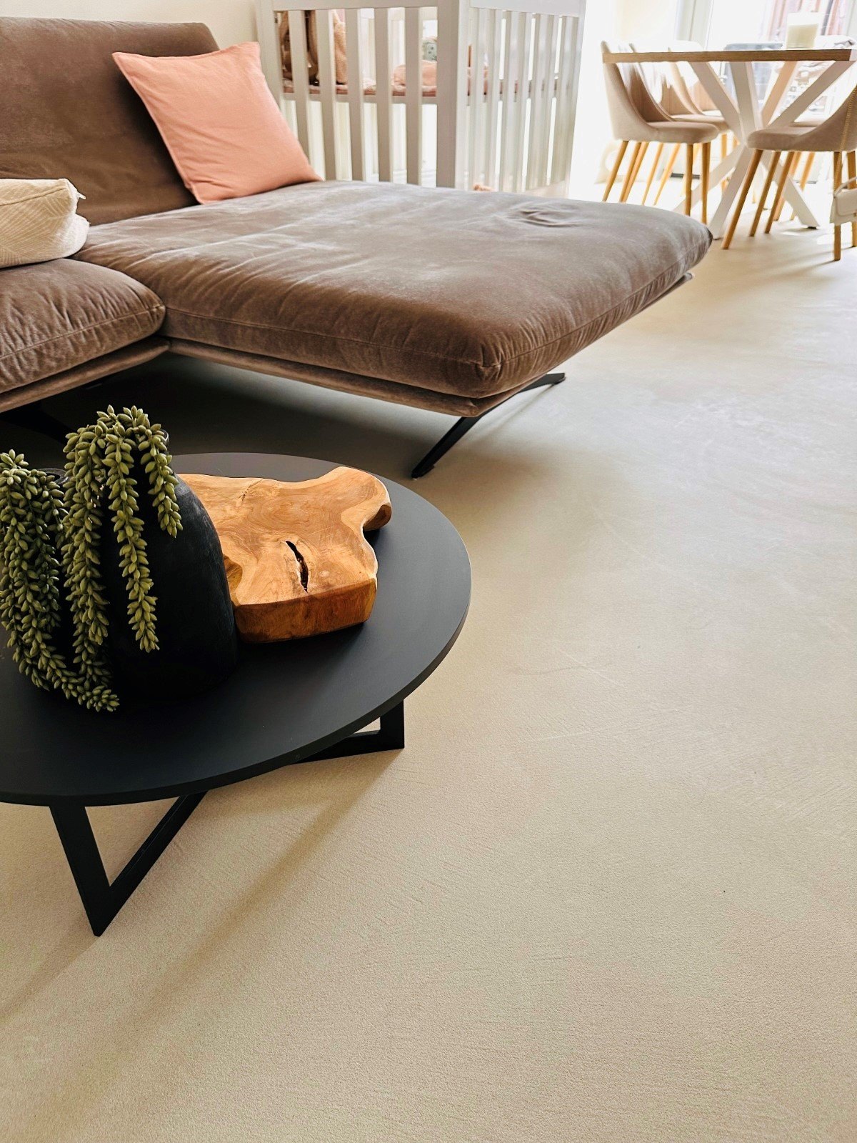 Solido kwartsiet gietvloer in Best in de zandkleur VEIL, met bruine velours bank en zwarte salontafel in een modern Japandi interieur.