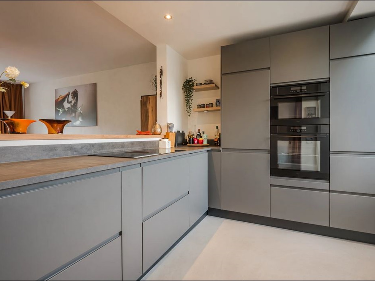 Moderne keuken met grijze fronten en een naadloze betonlook gietvloer in een zachte lichte tint