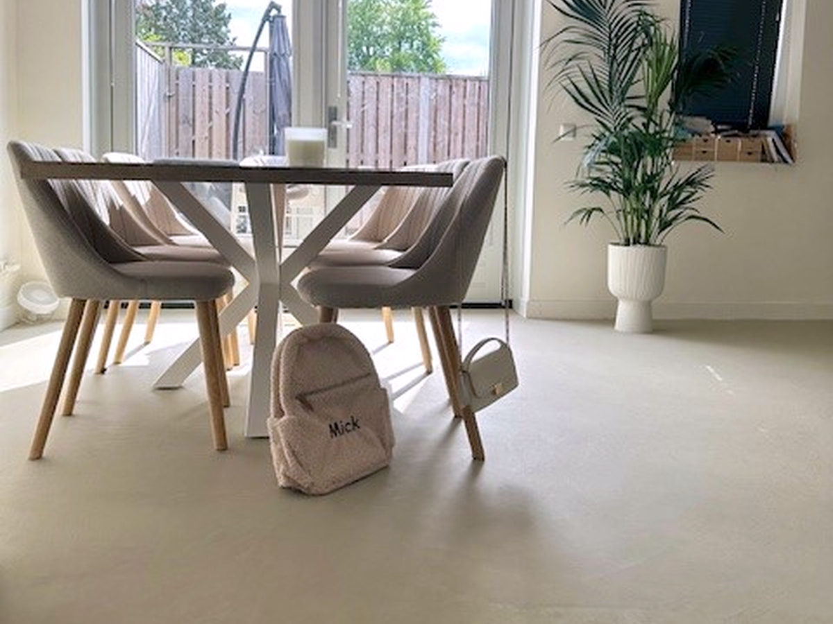 Solido kwartsiet gietvloer in Veil, eethoek bij de tuindeuren Eethoek bij openslaande tuindeuren met beige stoelen en een palm in witte pot op een Solido kwartsiet gietvloer in de kleur Veil