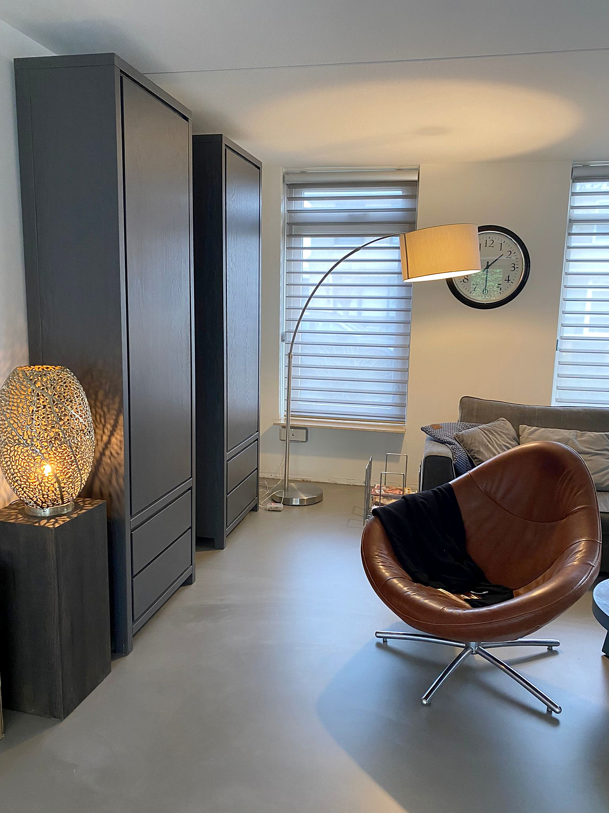 Living Quartz Stone gietvloer Emperador Grey met leren fauteuil Living Quartz Stone gietvloer in Emperador Grey met donkere kasten, booglamp en cognackleurige leren draaifauteuil